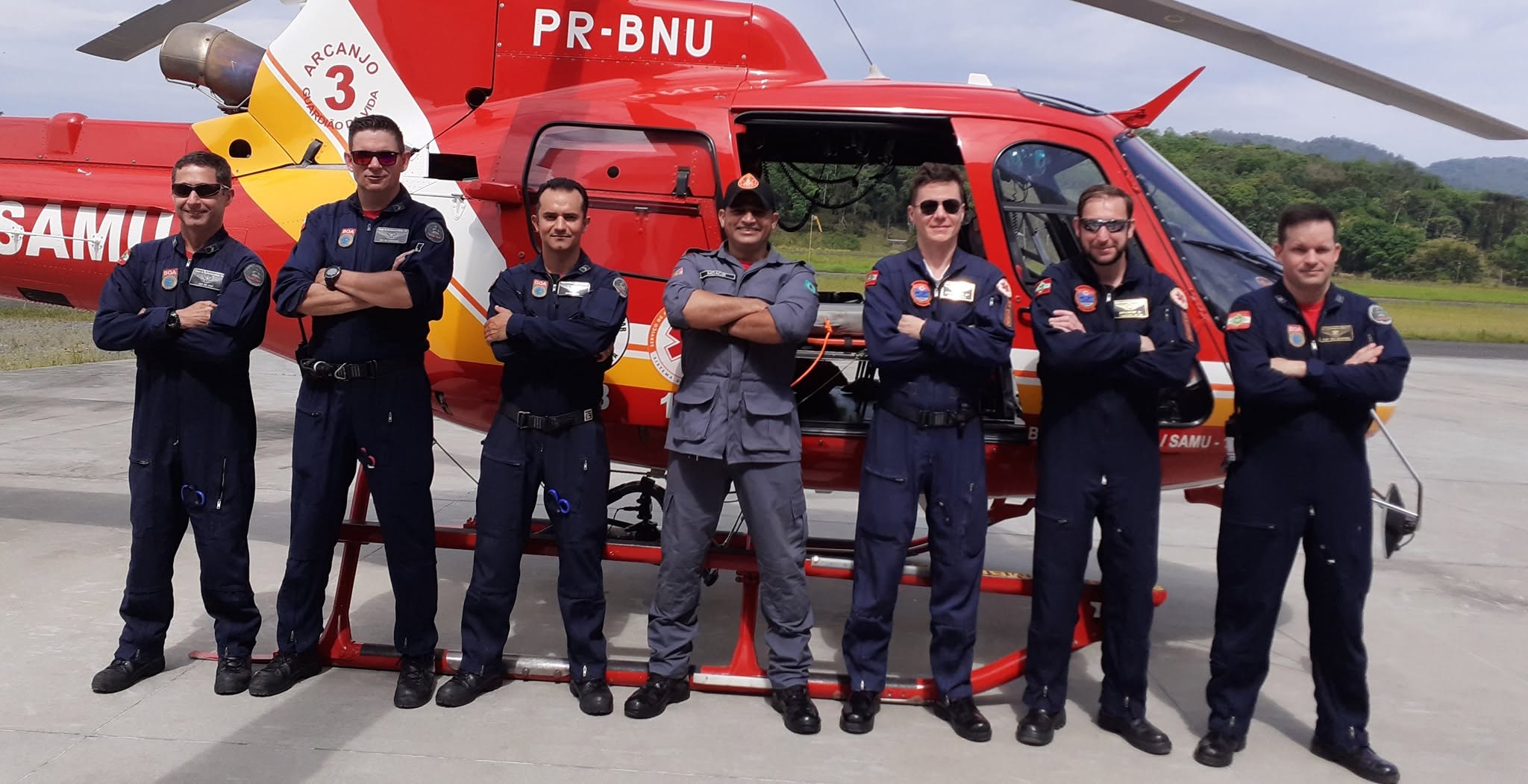 Equipe de bombeiros e socorristas ao lado do helicóptero Arcanjo do SAMU