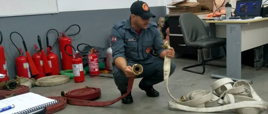 Instrutor apresentando mangueiras e extintores a uma turma