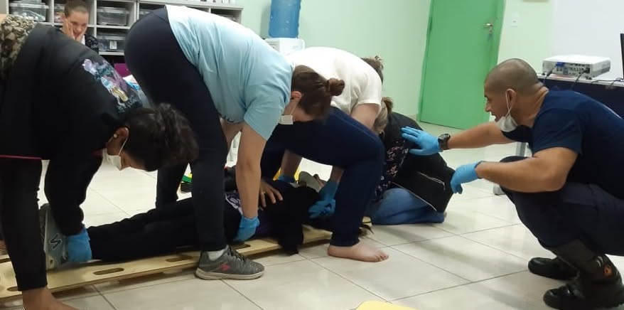 Alunos imobilizando uma vítima em prancha durante treinamento de primeiros socorros