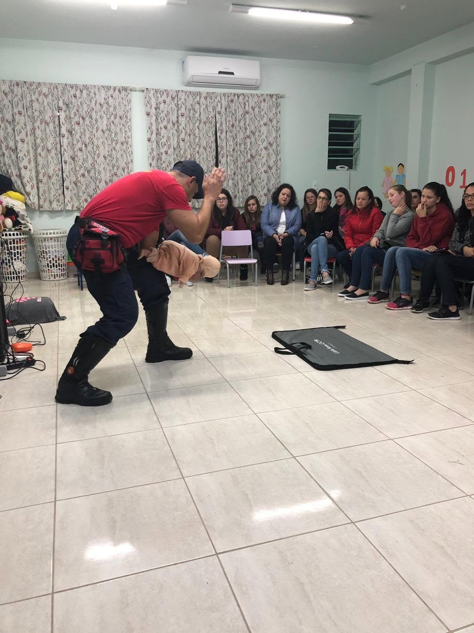 Instrutor demonstrando manobra de reanimação em manequim infantil para uma turma