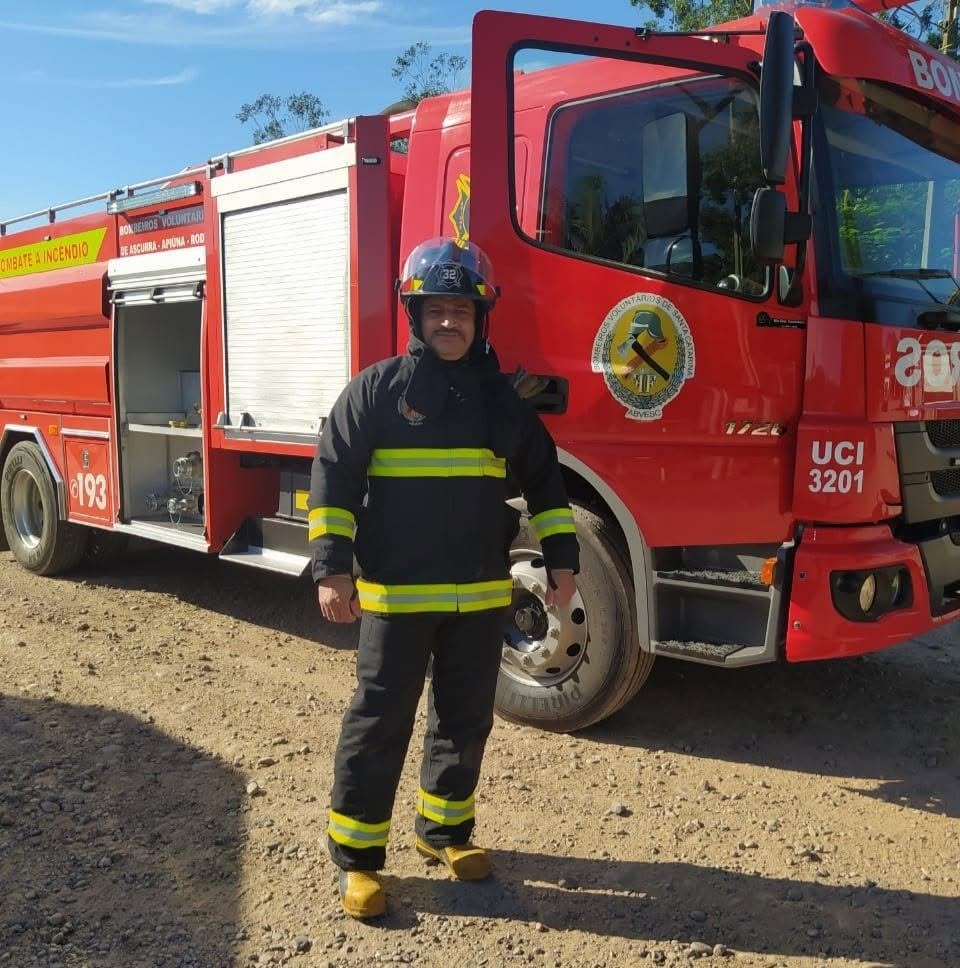 Bombeiro com equipamento completo ao lado de caminhão de combate a incêndio